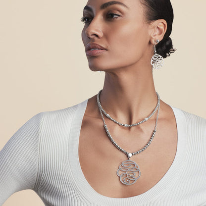Model wearing Brighton silver-plated drop earrings with hammered swirl design paired with a layered beaded pendant necklace