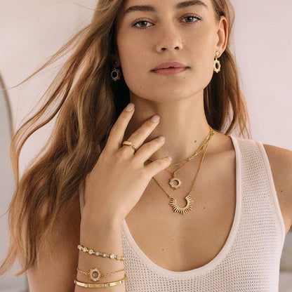 Model wearing Brighton gold-plated sunburst pendant necklaces with matching drop earrings and coordinating Brighton accessories