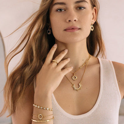 Model wearing Brighton gold-plated sunburst drop earrings and layered necklaces with coordinating Brighton accessories