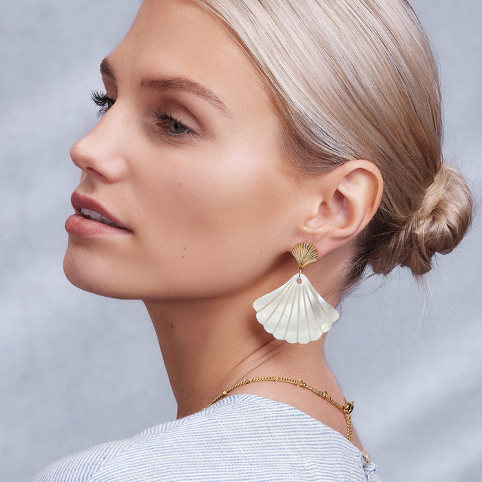 Model wearing Brighton drop earrings with gold-plated shell tops and large white shell-shaped fan pendants