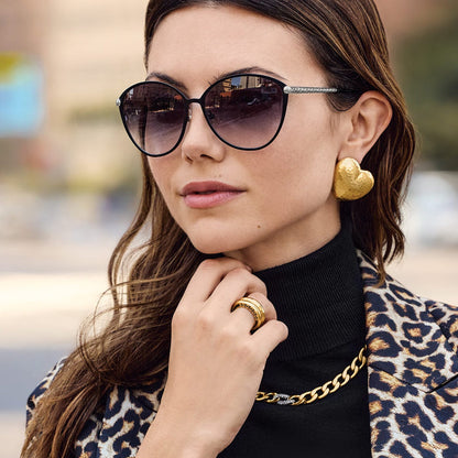 Model wearing Brighton sunglasses with black frames and silver-plated textured temples, styled with gold heart earrings