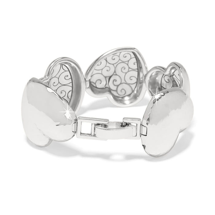 Brighton bracelet with silver-plated hammered heart-shaped links and scrollwork detail with hinged clasp on a white background