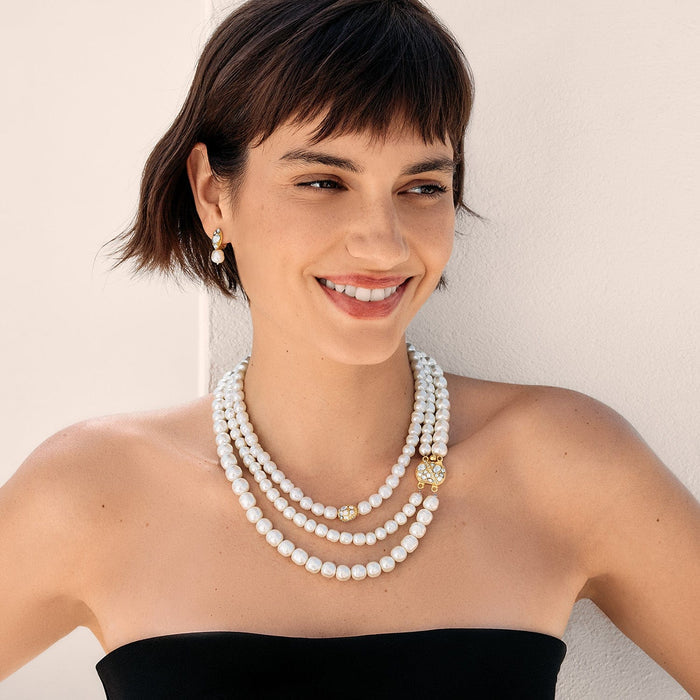 Model wearing a Brighton triple-strand pearl necklace with gold-plated crystal accents paired with matching pearl drop earrings